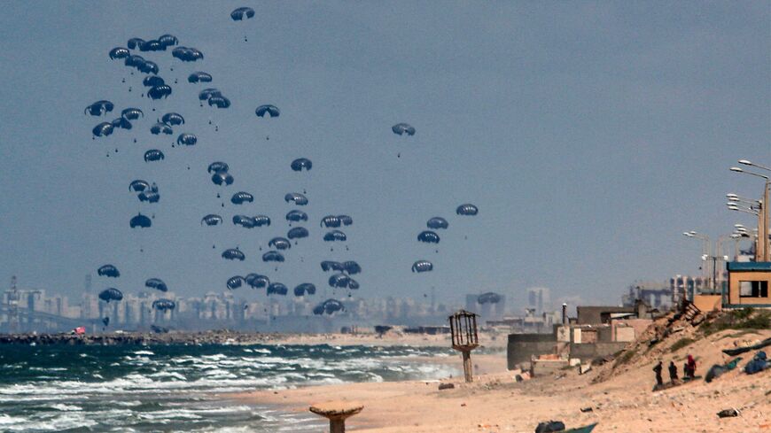 Humanitarian aid is dropped on the Gaza Strip, west of Gaza City, on March 25, 2024, amid the ongoing conflict in the Palestinian territory between Israel and the militant group Hamas, with the background showing Israel's Rutenberg power station near Ashkelon.